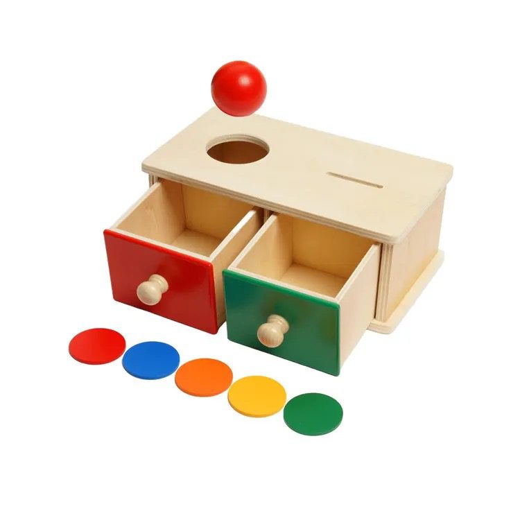 Wooden Montessori ball drop and coin slot toy with open red and green drawers and colorful discs