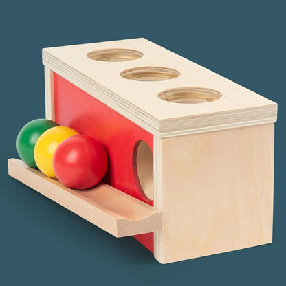 Montessori wooden ball push and slide box showing internal ball path for infant object permanence development