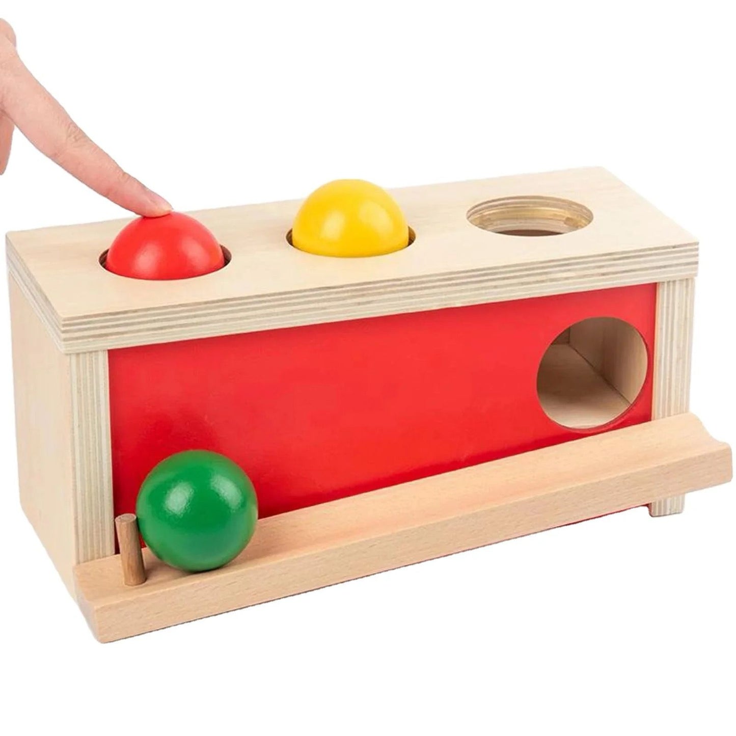 Montessori object permanence box with colored wooden ball being pressed into hole for infant hand eye coordination