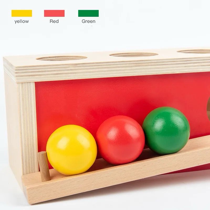 Montessori wooden object permanence ball box with yellow red and green balls collected in front tray