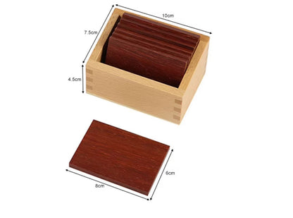 Dark wooden Montessori baric tablets inside a wooden storage box with labeled size measurements for tactile and pressure discrimination learning.