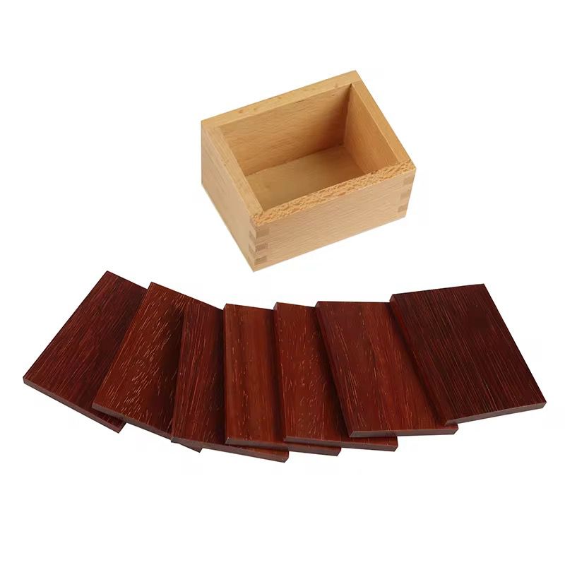 Single Montessori baric tablets wooden box with dark wooden weight tablets arranged in front for pressure and weight discrimination activities.