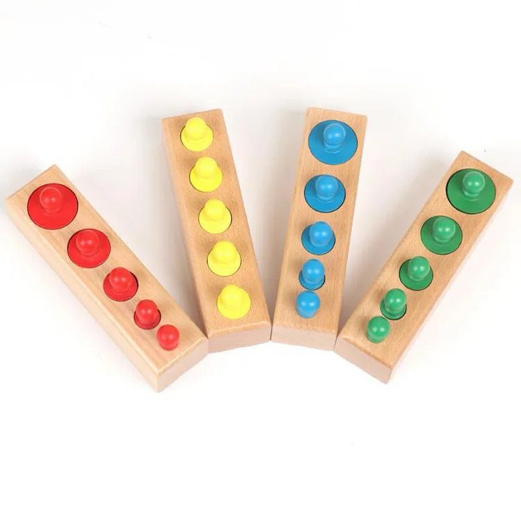 Four wooden trays with red, yellow, blue, and green Montessori knobbed cylinders arranged by size
