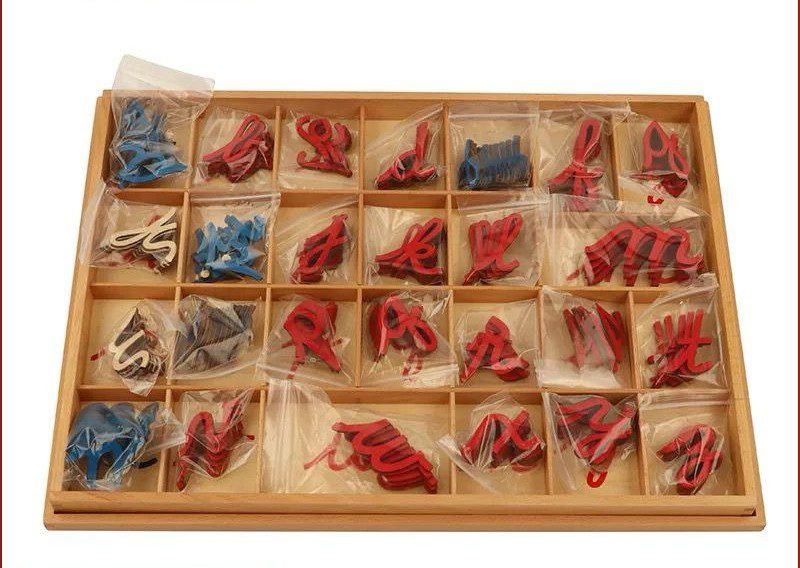 Wooden tray containing Montessori cursive movable alphabet letters individually packed in plastic bags