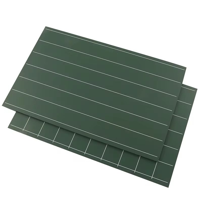 Two green Montessori double-sided chalkboards stacked together, showing writing lines and square grids for early handwriting practice.