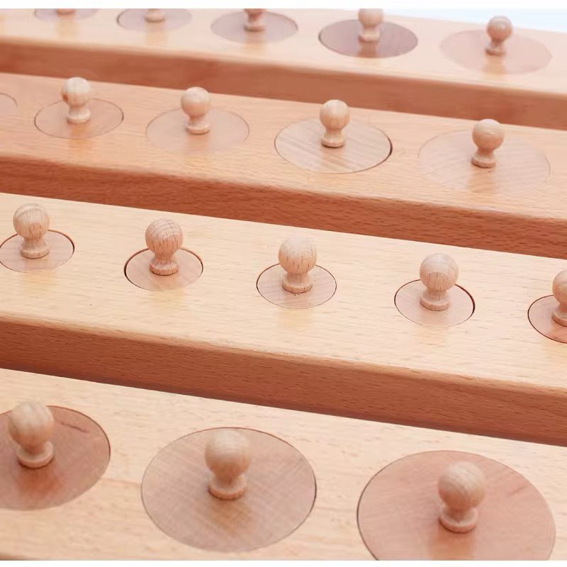 Close-up view of Montessori knobbed cylinder blocks showing wooden cylinders arranged in graded sizes