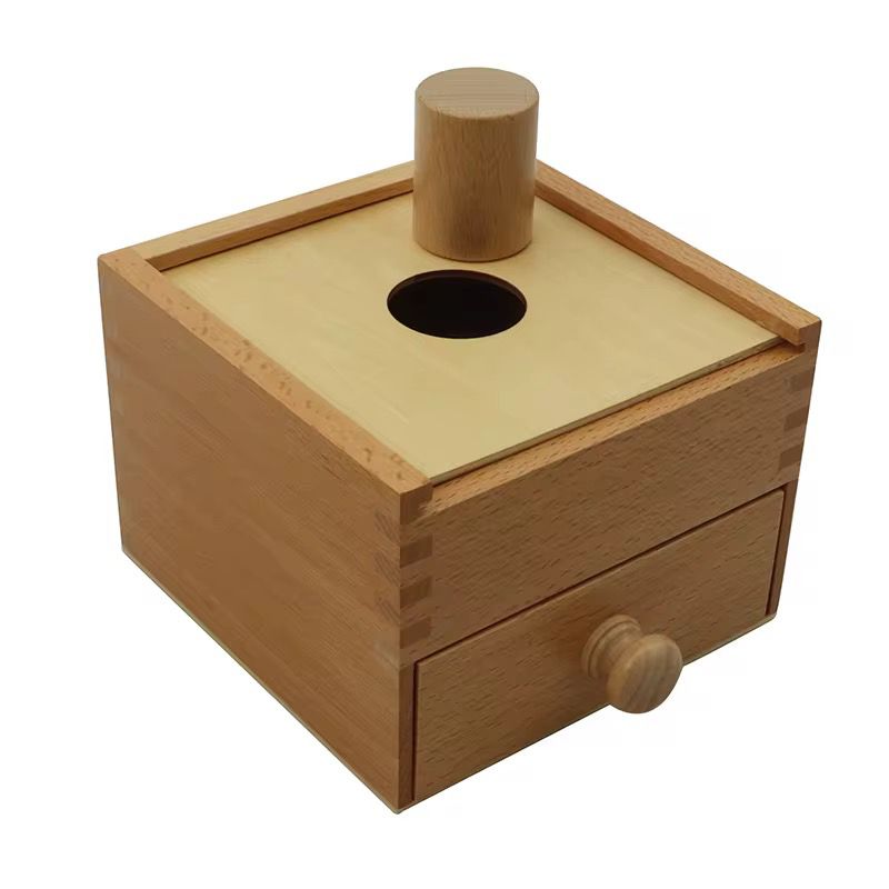 Montessori mailbox shape sorting activity showing cylinder object inserted for toddler fine motor and object permanence work