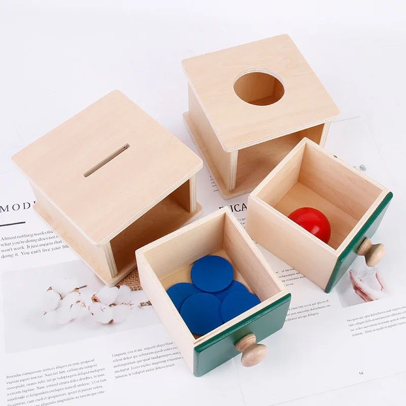 Open wooden Montessori object permanence box showing internal storage drawer with learning pieces