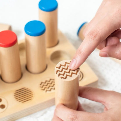Hand touching the engraved pattern on a Montessori wooden cylinder for tactile and visual matching