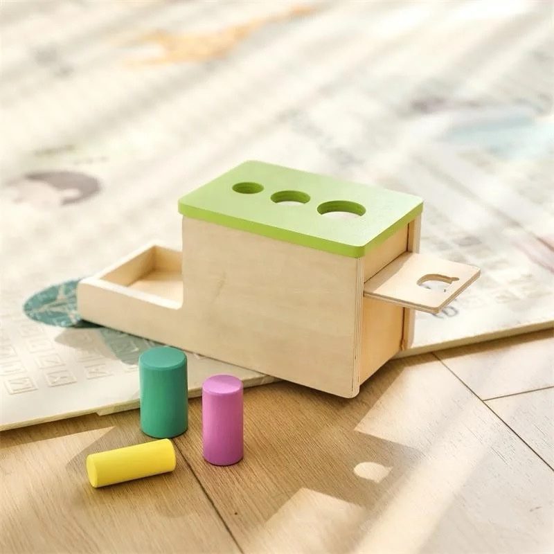 Side view of Montessori peg drop box with sliding tray for object retrieval