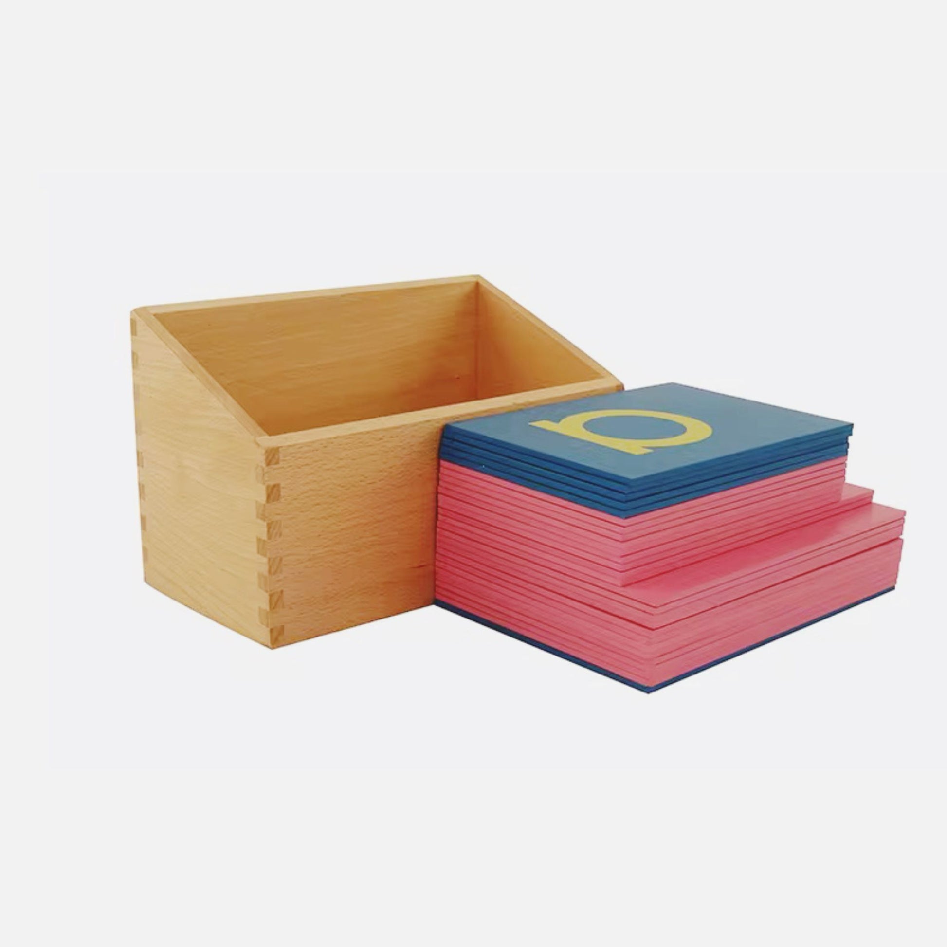 Wooden box with a neatly arranged stack of Montessori lowercase sandpaper letters placed beside it.