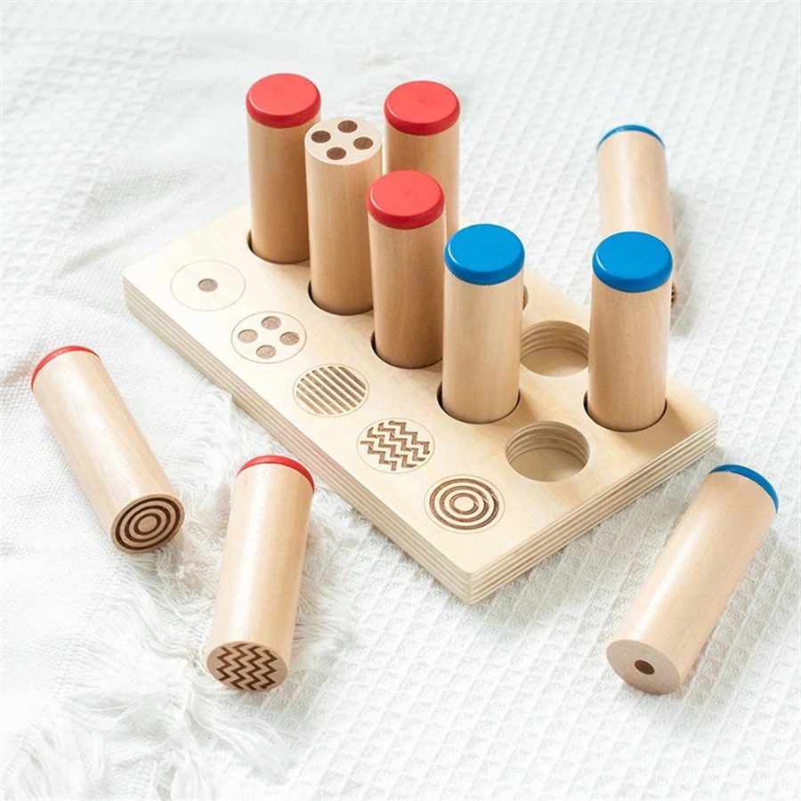 Montessori sound and pattern cylinders removed from tray for matching and sensory exploration.