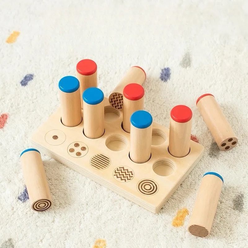 Children’s Montessori sound and pattern matching activity with wooden cylinders and engraved tray.