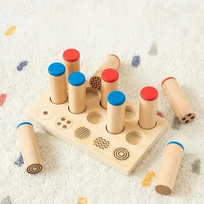 Children’s Montessori sound and pattern matching activity with wooden cylinders and engraved tray.