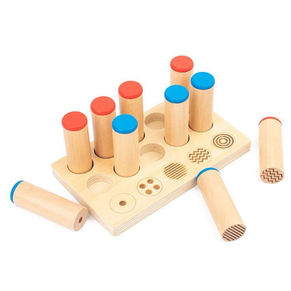 Wooden Montessori board with sound and pattern cylinders placed in matching slots