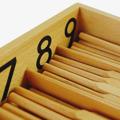 Close-up of Montessori spindle box showing wooden spindles grouped under numbers 7, 8, and 9.