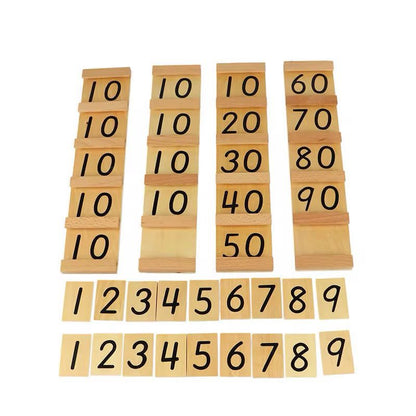 Wooden number tiles for Montessori Teen and Ten Boards, including tens and unit numerals laid out for counting practice.