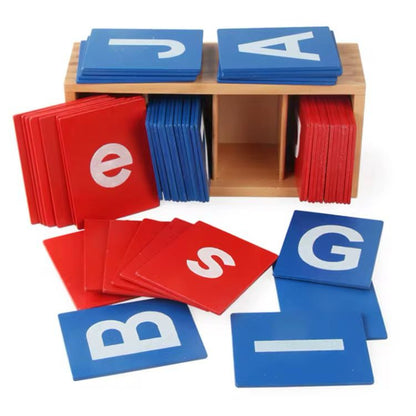 Montessori sandpaper letters in upper and lowercase displayed with a wooden storage box and red and blue tactile letter tiles.