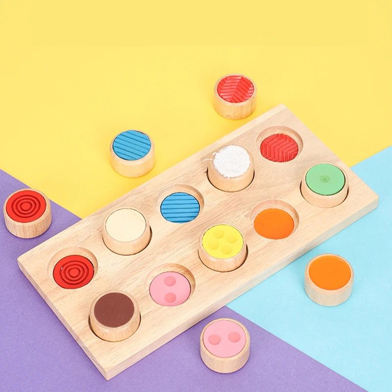 Wooden Montessori sensory texture board with colorful textured cylinders displayed on a bright background.