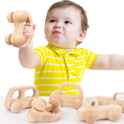 Infant holding natural wooden car toy for early grasping, movement exploration, and hand eye coordination