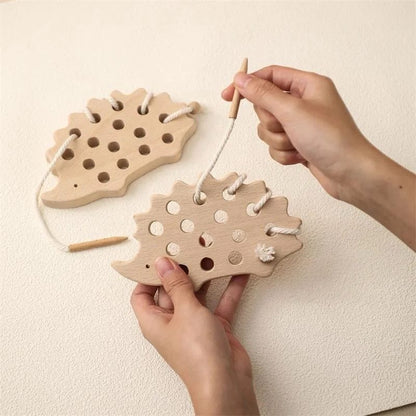 Wooden hedgehog lacing toy being threaded with string to develop toddler fine motor skills
