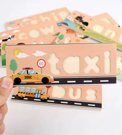 Close-up of wooden spelling puzzle board featuring the word taxi with letter cutouts and illustrated background