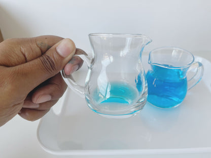 Hands-on Montessori pouring activity using glass pitchers to build coordination and control