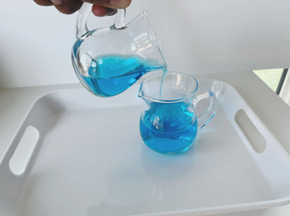 Montessori glass pitchers used for pouring activity to develop fine motor control and concentration in practical life work