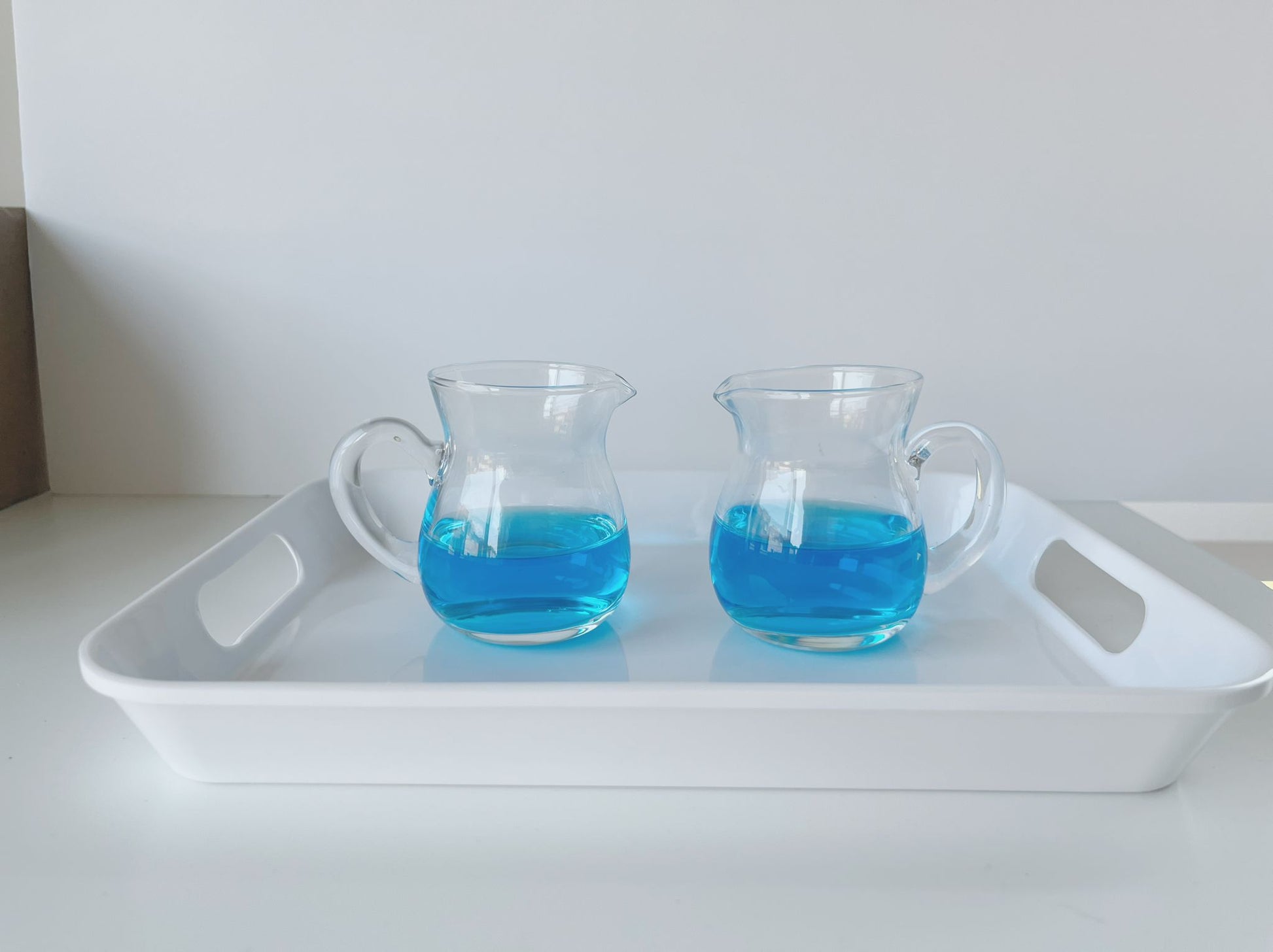 Set of Montessori glass pitchers arranged for practical life pouring exercises   
