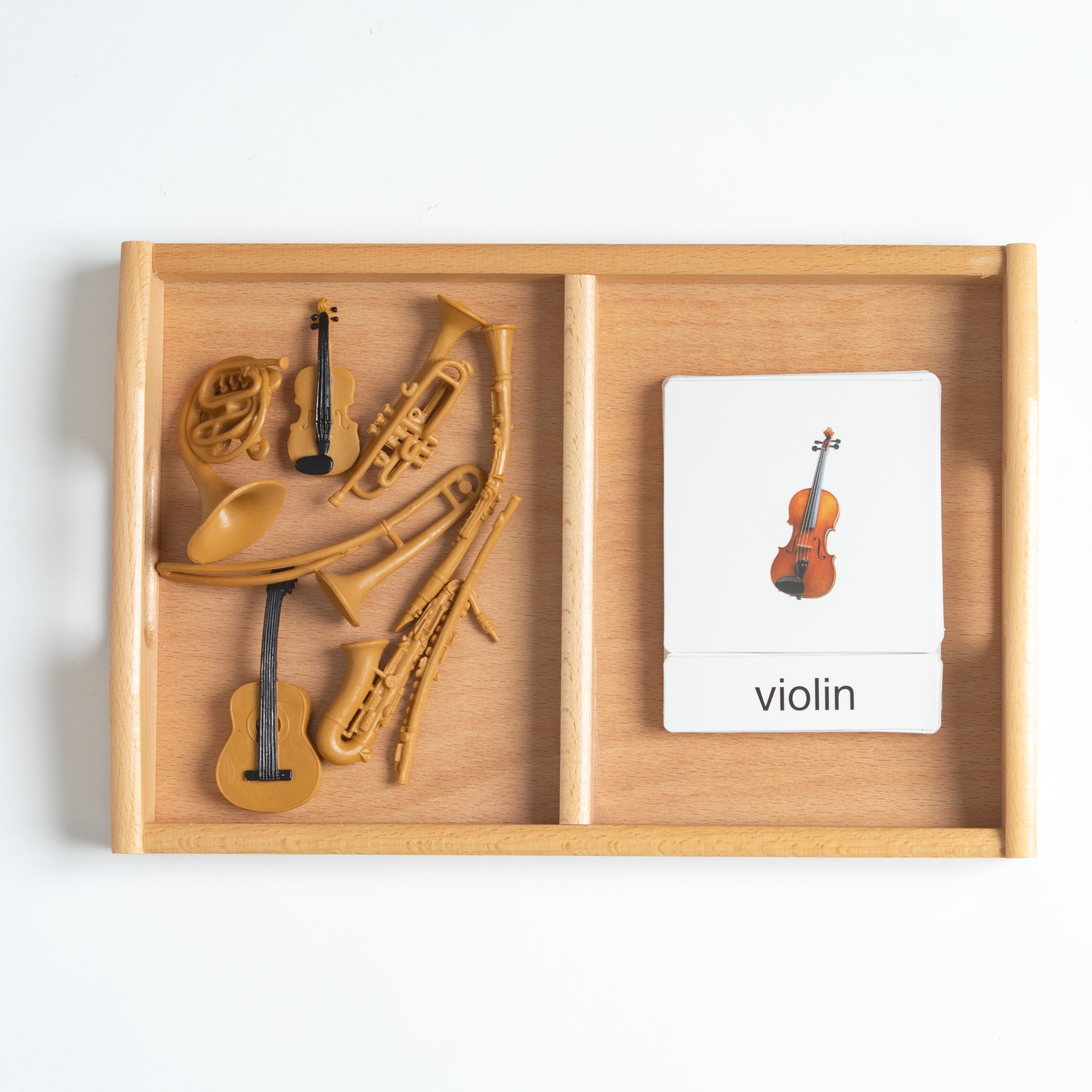 Montessori musical instruments classification set with mini instrument objects and 3-part nomenclature cards arranged on a wooden tray