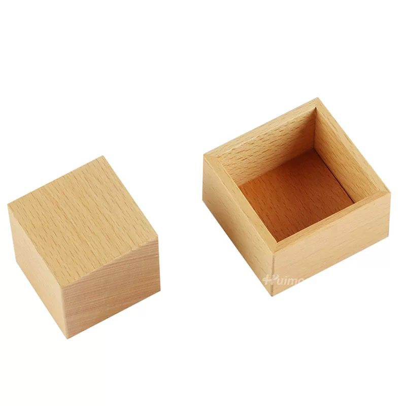 Natural wooden Montessori toy featuring a solid wooden cube block beside an open square wooden box on a light background.